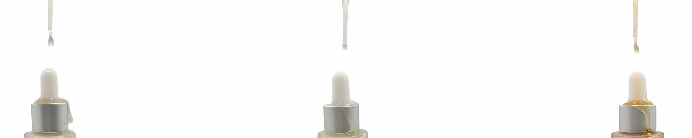 Set of three dropper bottles with white caps on a white background, with serums being dropped onto the bottle via the dropper.